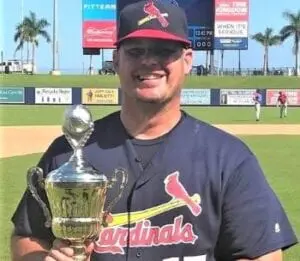 A baseball player holding a trophy on a baseball field.