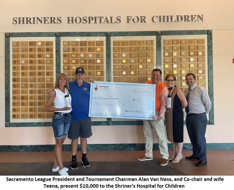 A group of people holding a check for shinners hospitals for children.