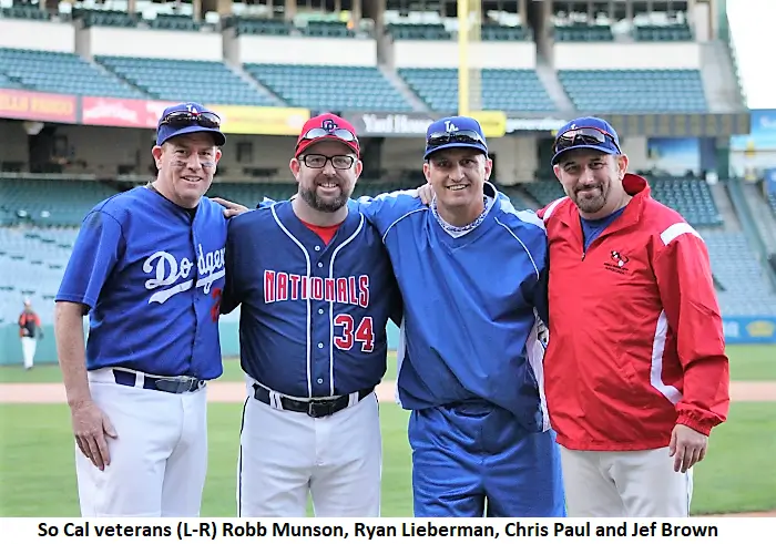 Four adult men in baseball uniforms representing the dodgers, nationals, and cardinals standing together on a baseball field, smiling.