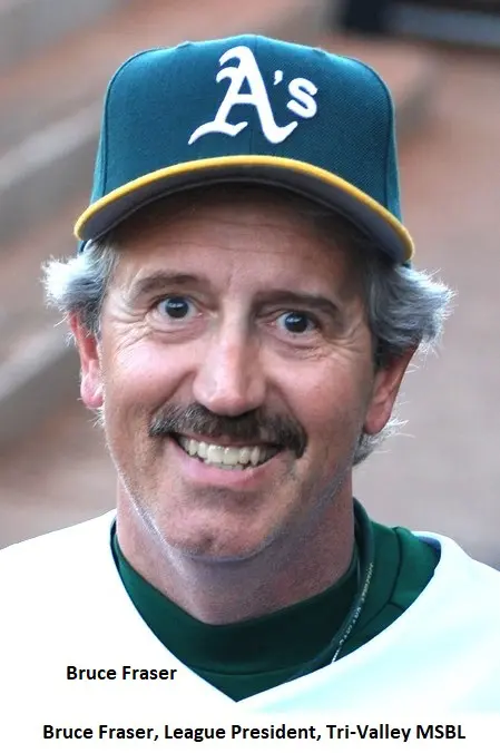 A man with a mustache in an oakland athletics cap, wearing a white and green jersey, smiling at the camera. name tag reads "bruce fraser, league president, tri-valley msbl.