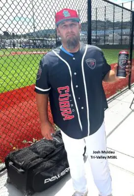 Baseball player holding a drink by field.