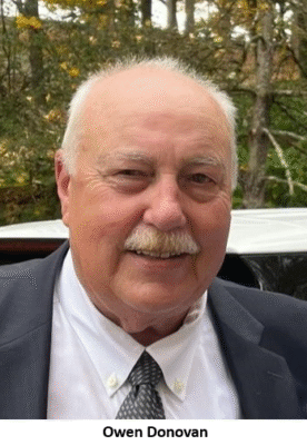 Elderly man smiling outdoors in suit.