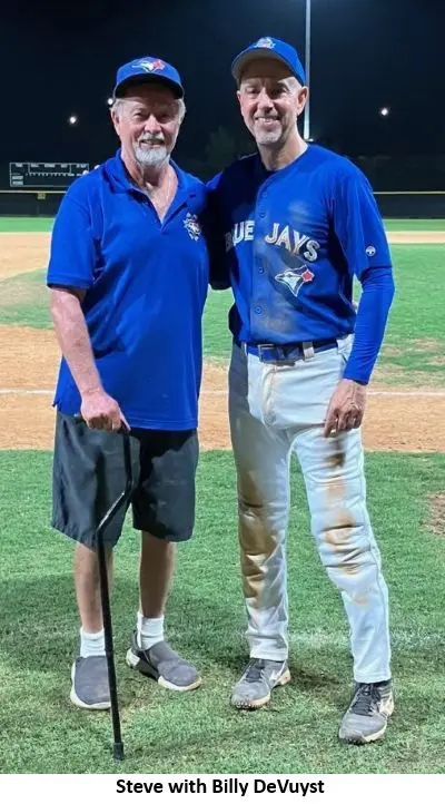 Two men on a baseball field smiling.