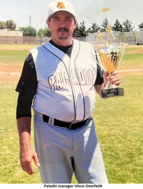 Baseball coach holding a trophy on field.